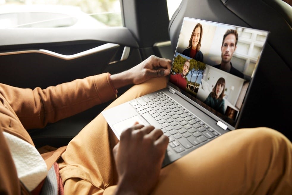 Someone sitting in the backseat of car using the Lenovo Yoga 5G laptop. Screen shows a live video conference.