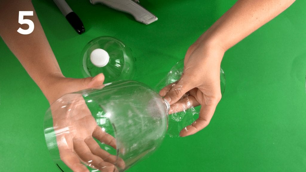 Secure plastic wrap around the bottom of the soda bottle with a rubber band. 