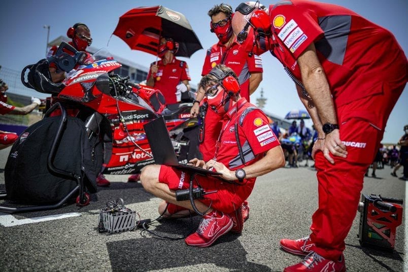 Tardozzi with a team of technicians on the MotoGP track reviewing data.