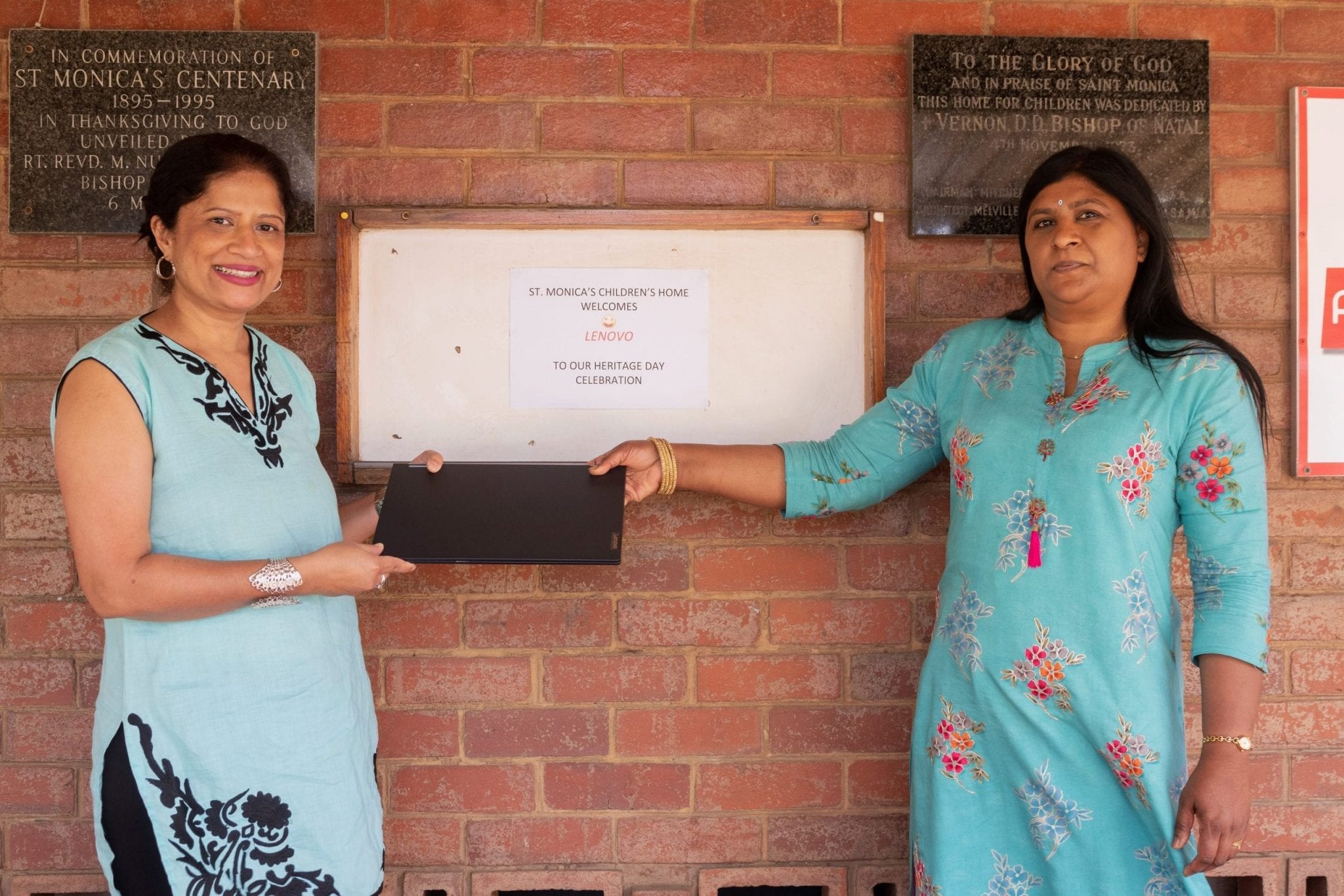 Althea Daniels receives a Lenovo laptop from Jane Govindsamy outside St. Monica's.