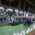 Hero MotoCorp assembly line, wide shot with multiple people working on dozens of motorcycles.