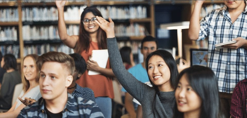 Students raising hands in classroom